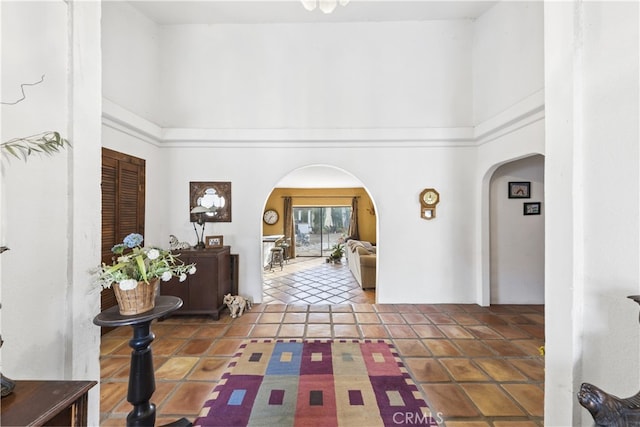 hallway featuring tile patterned flooring and a high ceiling