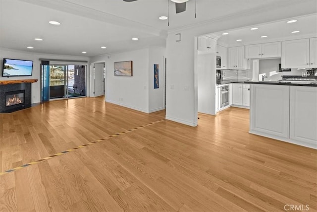 unfurnished living room with crown molding, light hardwood / wood-style flooring, and ceiling fan