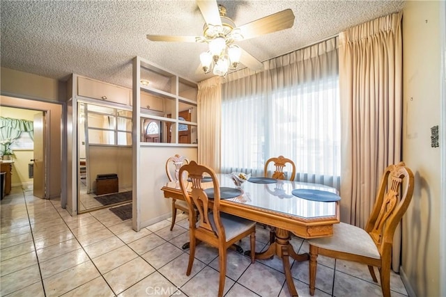 tiled dining space with ceiling fan and a textured ceiling