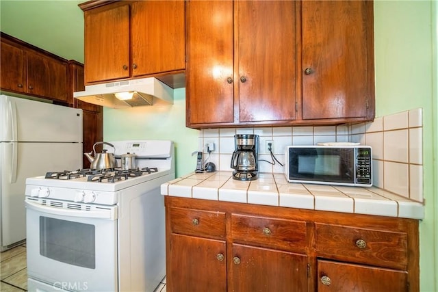 kitchen with white appliances, tile counters, and decorative backsplash