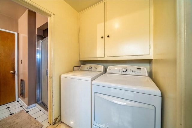 clothes washing area featuring light tile patterned flooring, cabinets, and separate washer and dryer