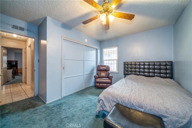 carpeted bedroom featuring ceiling fan, a closet, and a textured ceiling