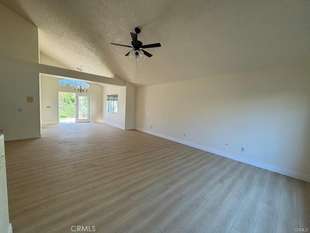 spare room featuring lofted ceiling, ceiling fan with notable chandelier, a textured ceiling, and light wood-type flooring