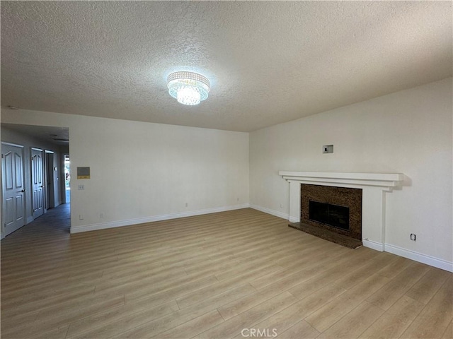 unfurnished living room with a textured ceiling and light hardwood / wood-style floors