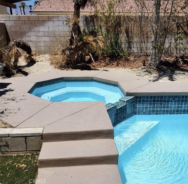 view of swimming pool with an in ground hot tub