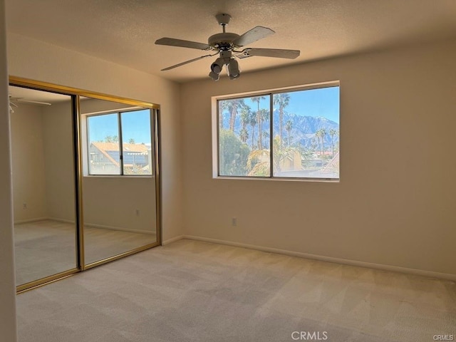 unfurnished bedroom with a closet, a mountain view, light carpet, and a textured ceiling