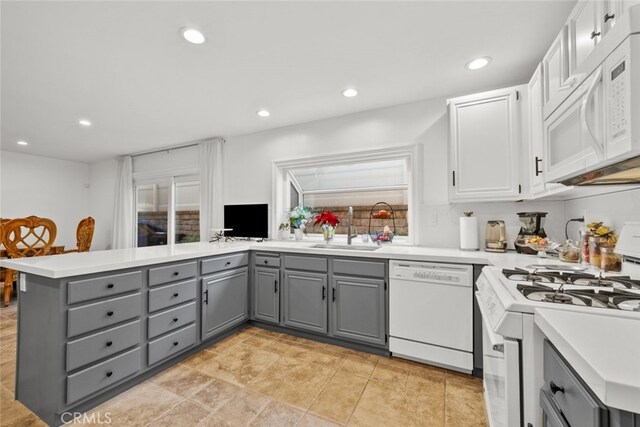 kitchen with sink, white appliances, white cabinetry, gray cabinetry, and kitchen peninsula