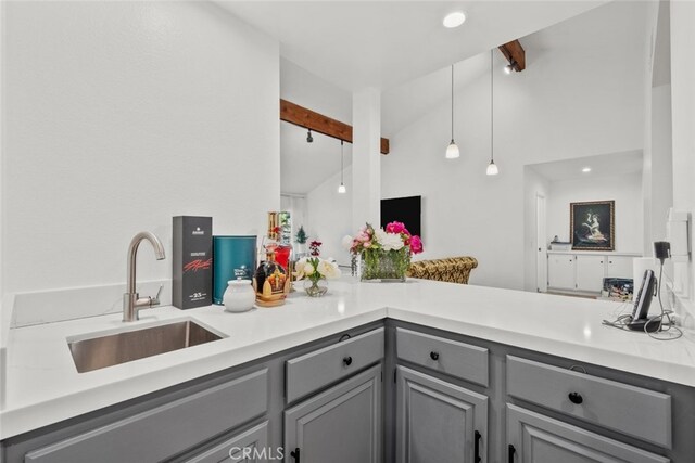 kitchen with pendant lighting, sink, gray cabinets, vaulted ceiling with beams, and kitchen peninsula