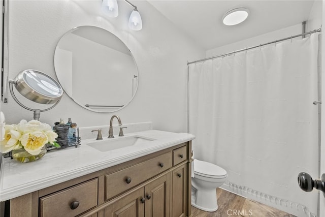 bathroom with wood-type flooring, vanity, and toilet