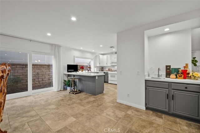 kitchen with a breakfast bar, sink, white stove, gray cabinetry, and white cabinets