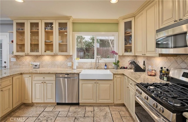 kitchen featuring sink, cream cabinets, stainless steel appliances, and light stone countertops