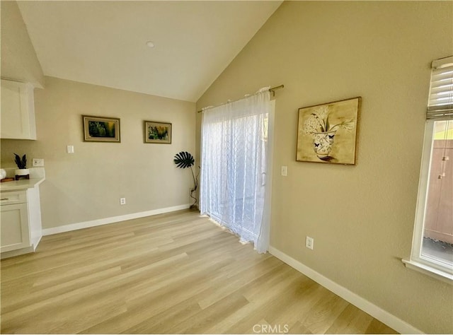 unfurnished dining area with lofted ceiling and light hardwood / wood-style flooring