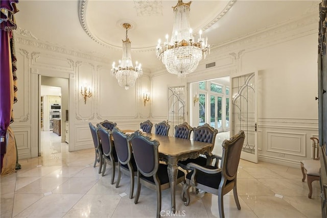 dining room featuring an inviting chandelier, visible vents, a decorative wall, crown molding, and wainscoting