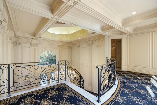 hallway with beam ceiling, an upstairs landing, ornamental molding, and a decorative wall