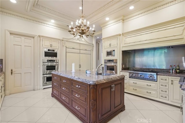 kitchen with ornamental molding, light tile patterned flooring, pendant lighting, appliances with stainless steel finishes, and cream cabinets