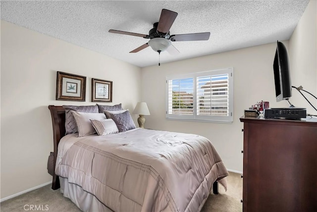 bedroom with ceiling fan, light colored carpet, and a textured ceiling