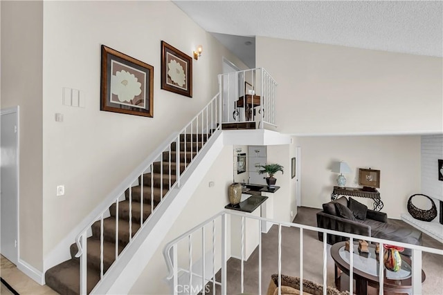 stairs featuring high vaulted ceiling and a textured ceiling