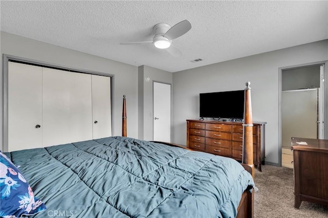 bedroom featuring light carpet, a textured ceiling, a closet, and ceiling fan