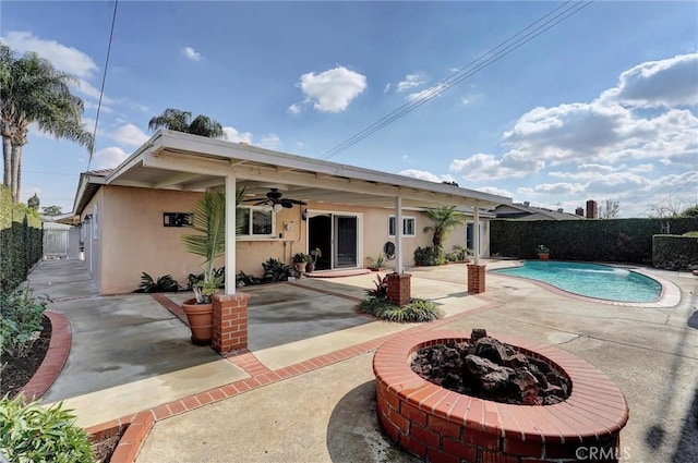 back of property featuring a fenced in pool, a patio area, ceiling fan, and a fire pit