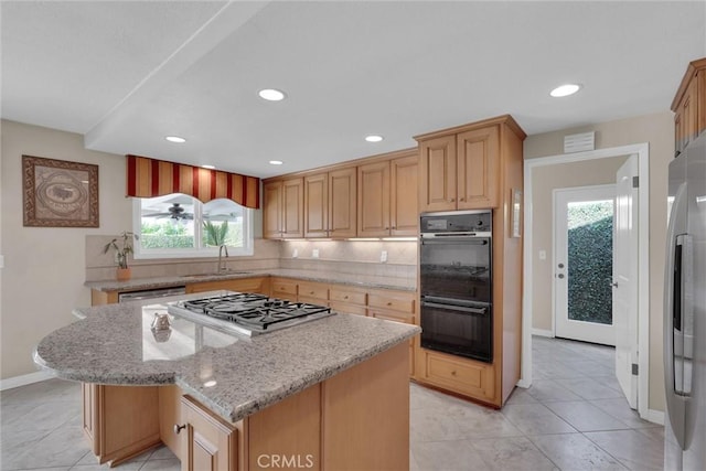 kitchen with sink, a center island, appliances with stainless steel finishes, light stone countertops, and decorative backsplash