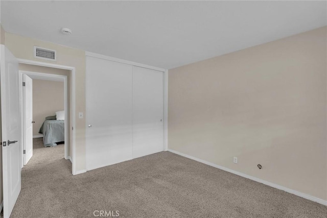 unfurnished bedroom featuring light colored carpet and a closet