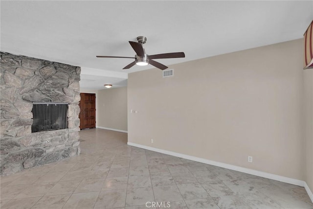 unfurnished living room with a stone fireplace and ceiling fan