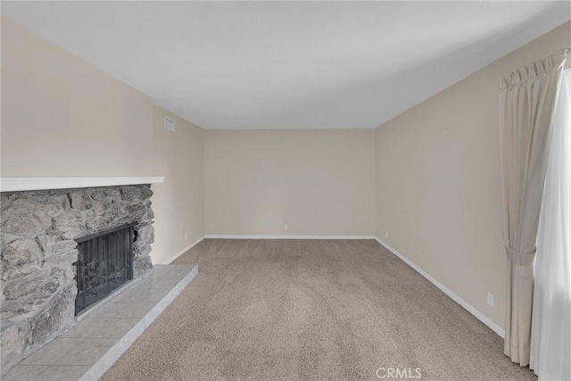 unfurnished living room with a stone fireplace and light carpet