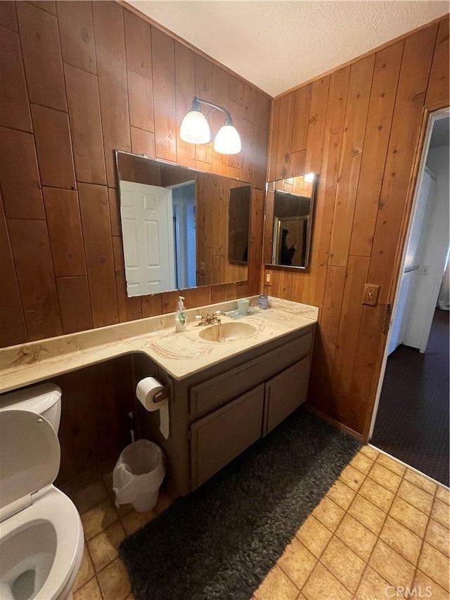 bathroom with vanity, toilet, and wood walls