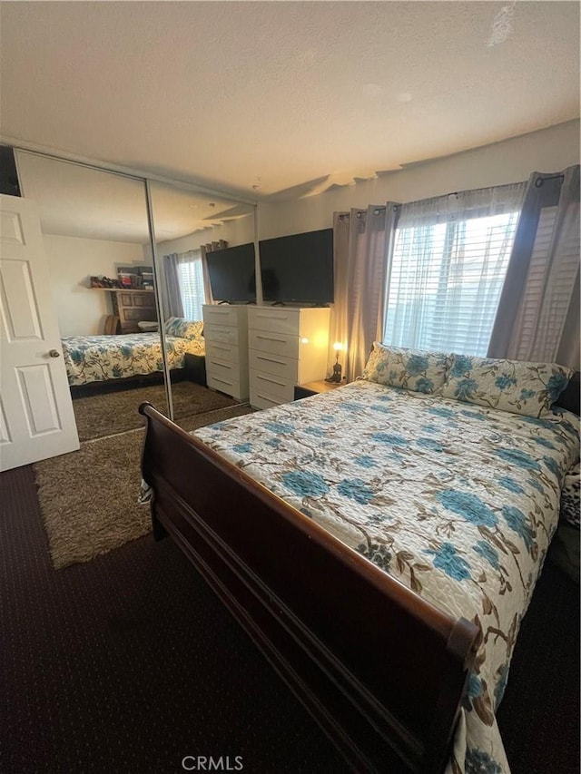 bedroom with carpet floors, a textured ceiling, and a closet