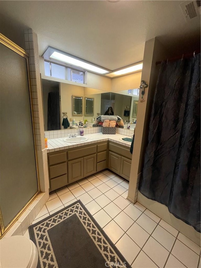 bathroom featuring vanity, a shower with door, tile patterned floors, and toilet