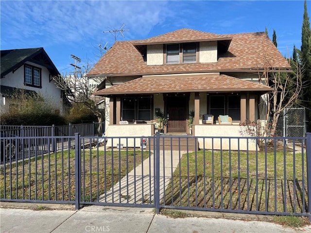 view of front facade with a fenced front yard, a porch, a shingled roof, and stucco siding