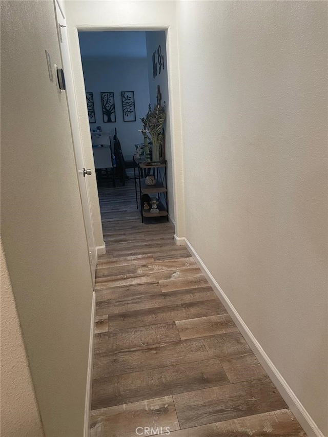 corridor featuring wood finished floors and baseboards