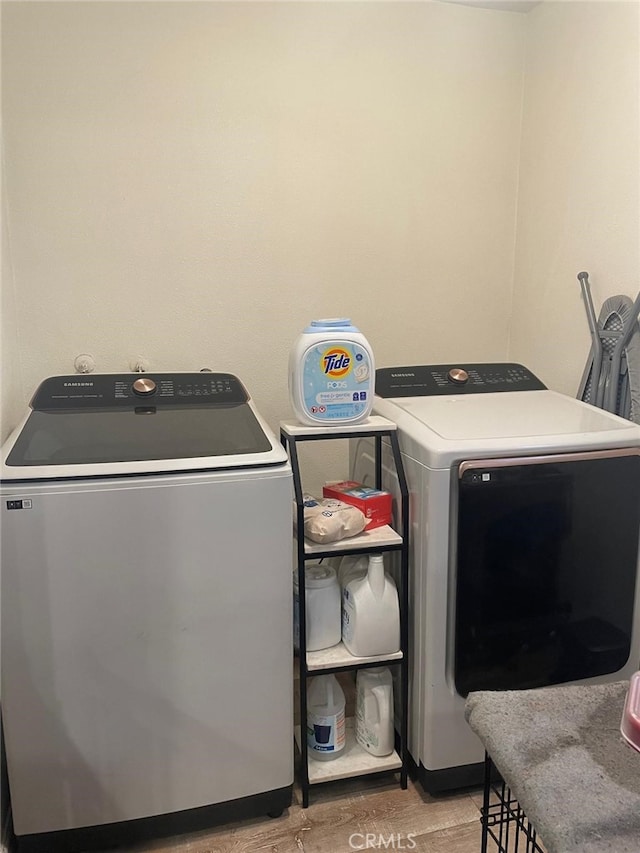 clothes washing area with light wood-type flooring, laundry area, and washing machine and clothes dryer