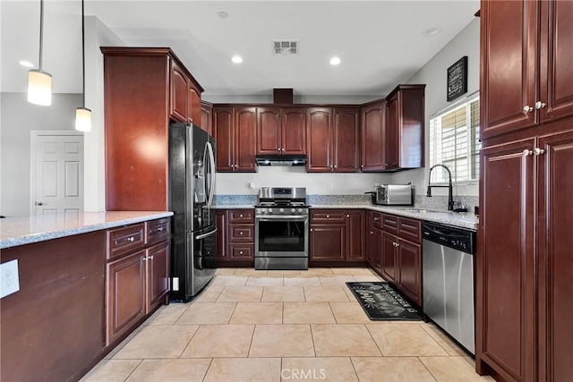 kitchen featuring stainless steel appliances, light stone countertops, sink, and decorative light fixtures