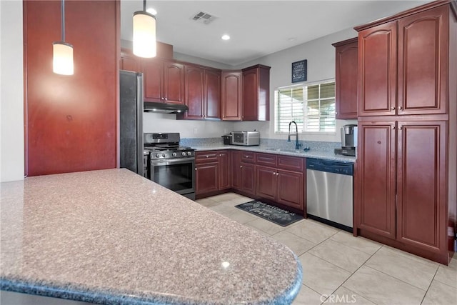 kitchen with pendant lighting, sink, appliances with stainless steel finishes, light stone countertops, and light tile patterned flooring