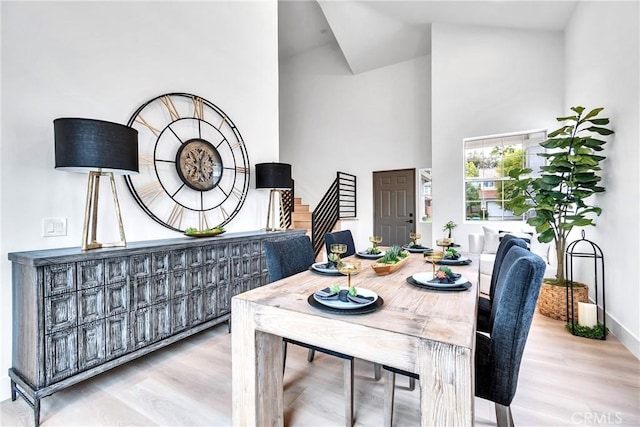 dining room with a towering ceiling and light hardwood / wood-style floors