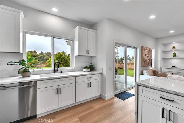 kitchen featuring dishwasher, sink, white cabinets, a healthy amount of sunlight, and light hardwood / wood-style flooring