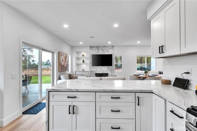 kitchen featuring light stone countertops, light wood-type flooring, and white cabinets