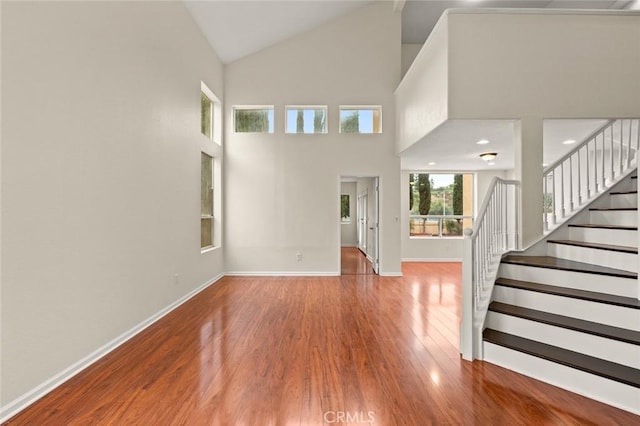 foyer entrance with hardwood / wood-style floors and high vaulted ceiling