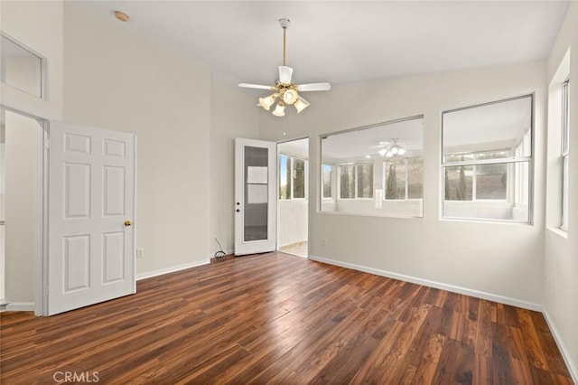 empty room featuring vaulted ceiling, dark wood-type flooring, a wealth of natural light, and ceiling fan