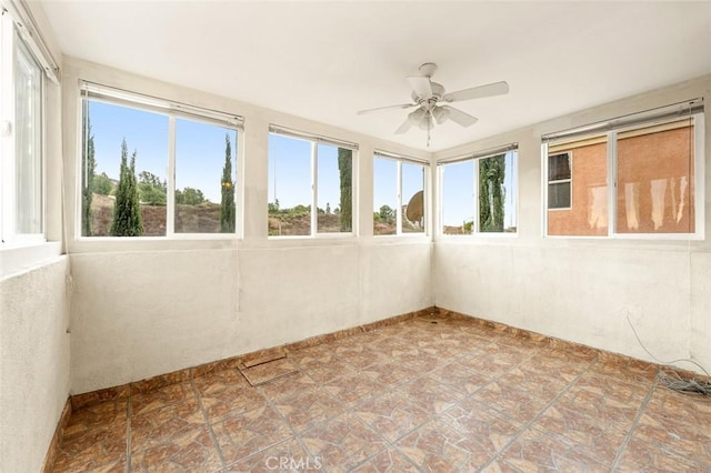 unfurnished sunroom featuring ceiling fan and a wealth of natural light