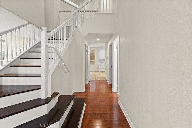 staircase with a high ceiling and wood-type flooring