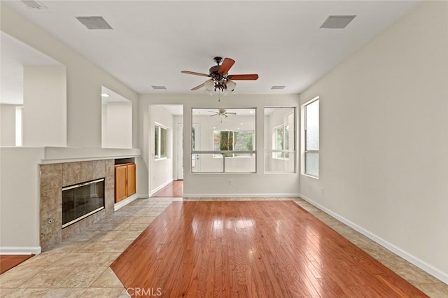 unfurnished living room featuring ceiling fan, a fireplace, and light hardwood / wood-style floors