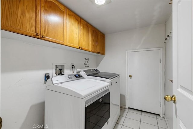 laundry room with cabinets, washer and dryer, and light tile patterned floors