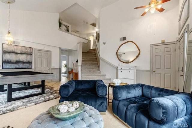 carpeted living room with ceiling fan and high vaulted ceiling