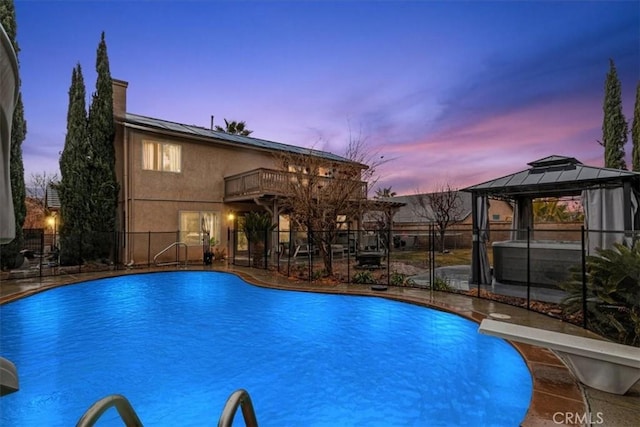 pool at dusk with a gazebo and a diving board