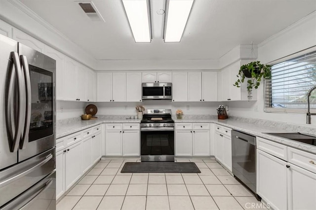 kitchen with light tile patterned flooring, appliances with stainless steel finishes, sink, white cabinets, and light stone countertops