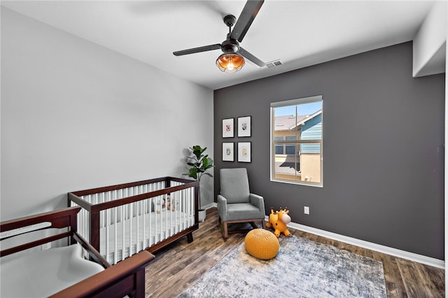 bedroom featuring a crib, hardwood / wood-style flooring, and ceiling fan