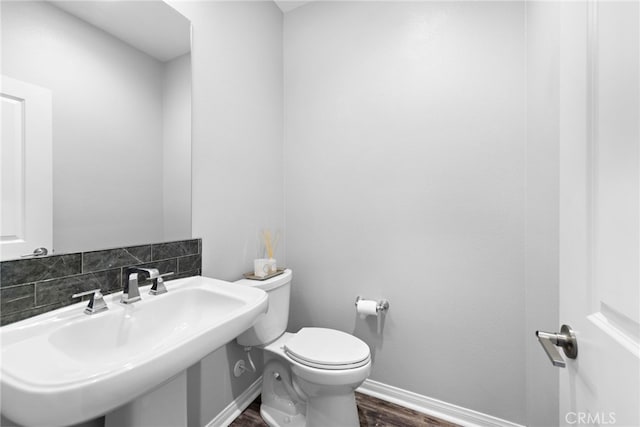 bathroom with wood-type flooring, backsplash, toilet, and sink