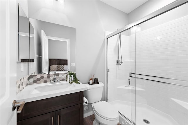 bathroom with vanity, tasteful backsplash, toilet, and a shower with shower door